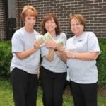 3 smiling women holding cash