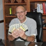 Smiling man at desk holding money