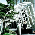 woman standing in from of truss structure by building