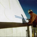 worker measuring building on ladder